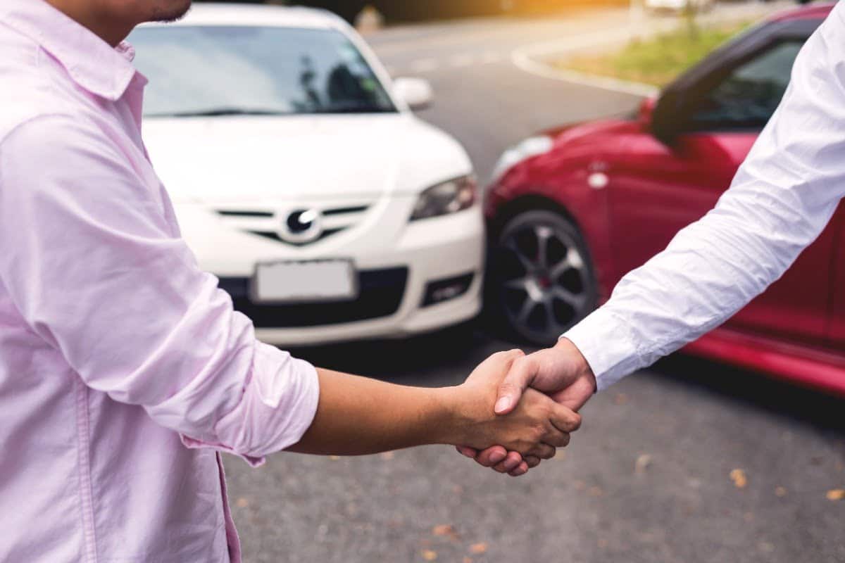 two hands shaking and two cars